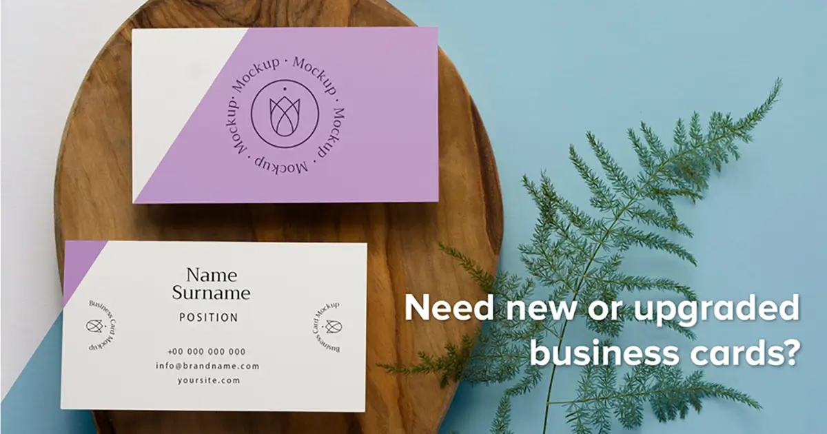 Custom business cards with a light blue geometric design, one standing upright and one lying flat showing contact details and a QR code