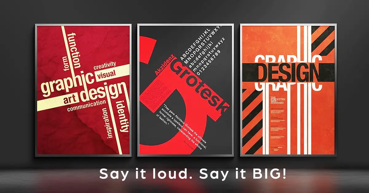 Three framed graphic design posters in red, dark grey and orange displayed on a dark wall