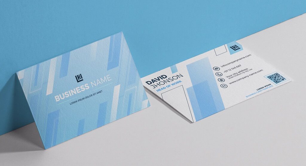 Custom business cards with a light blue geometric design, one standing upright and one lying flat showing contact details and a QR code