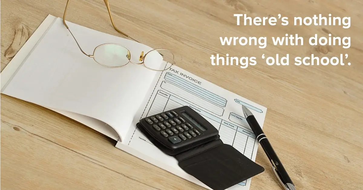 Printed NCR book on a wooden desk with a calculator, glasses and a pen